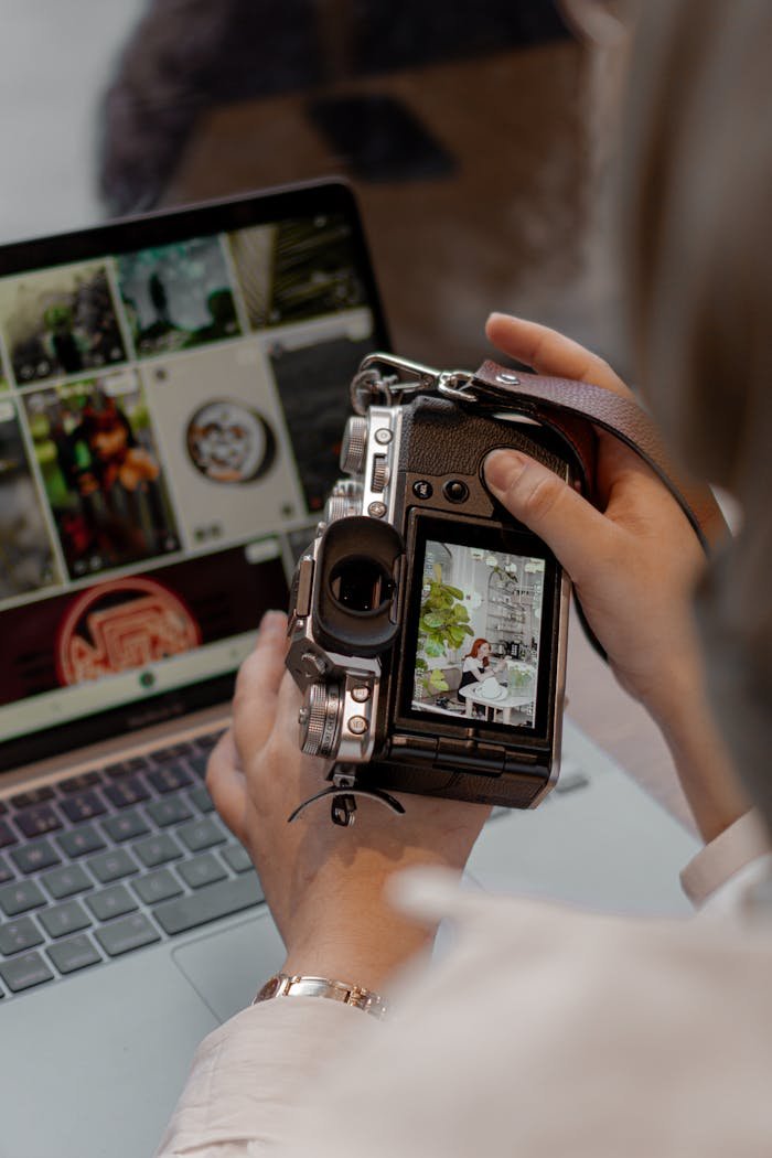 Close-up of a person using a digital camera and laptop for photo editing.